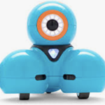 A small blue robot on wheels. A round ball with one circle shaped eye framed in orange is on the head of the robot. The neck is a black triangular shaped black bib with a small white and light blue triangle in center. Two ball shapes on wheels with flat bottoms for the legs directly under the head.