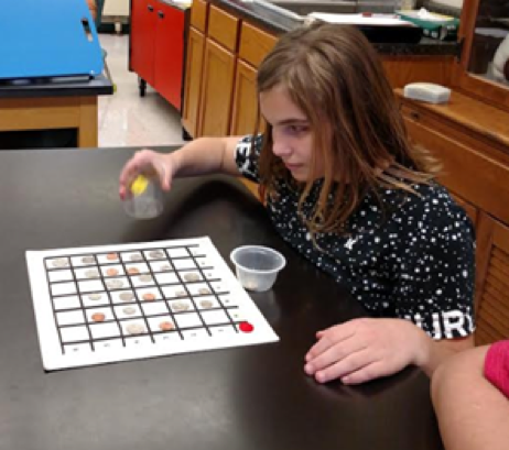 A student sitting at a table with a bingo card in front of her.