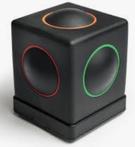 A black square plastic box with a raised circle on top and 4 sides. Each circle is outline with a different color: orange, red and green are seen in the photo.