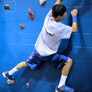 Student climbing a rock wall.