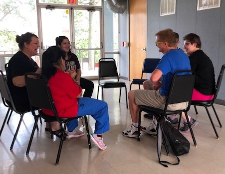 Students sitting in a circle discussing drama.