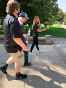 two students walking on a college campus getting a tour from a student at the college