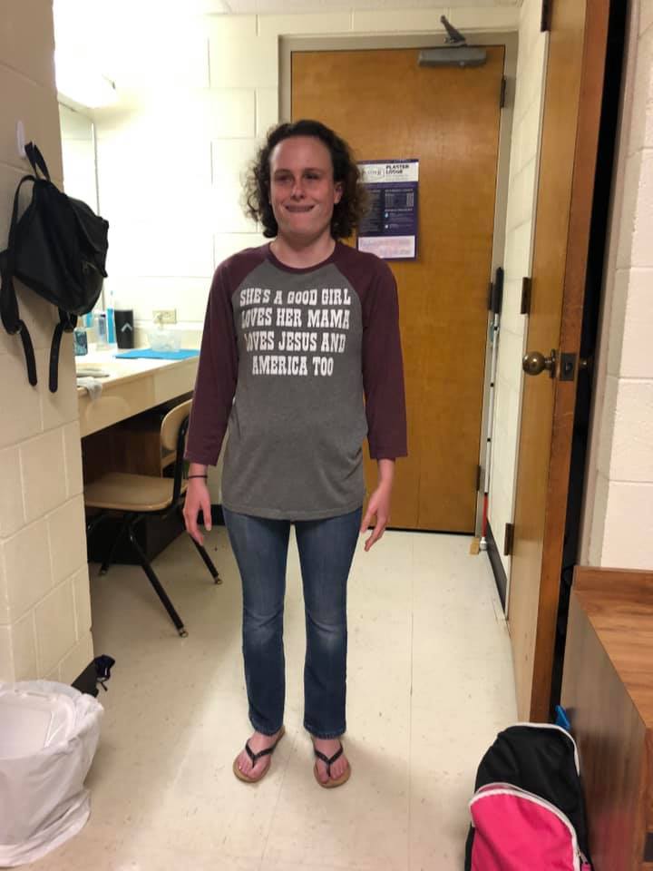 Gracie posing in her dorm room wearing flip flops, jeans and long sleeved t-shirt