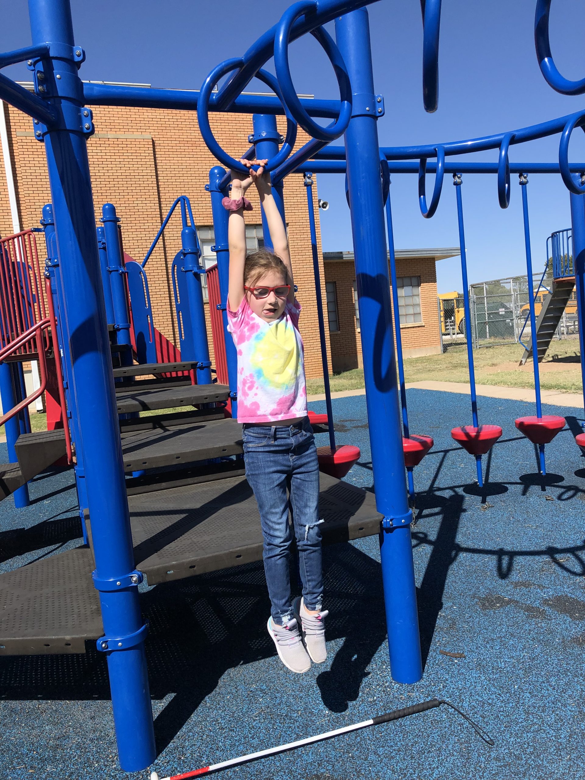 girl hanging from monkey bars at school playground