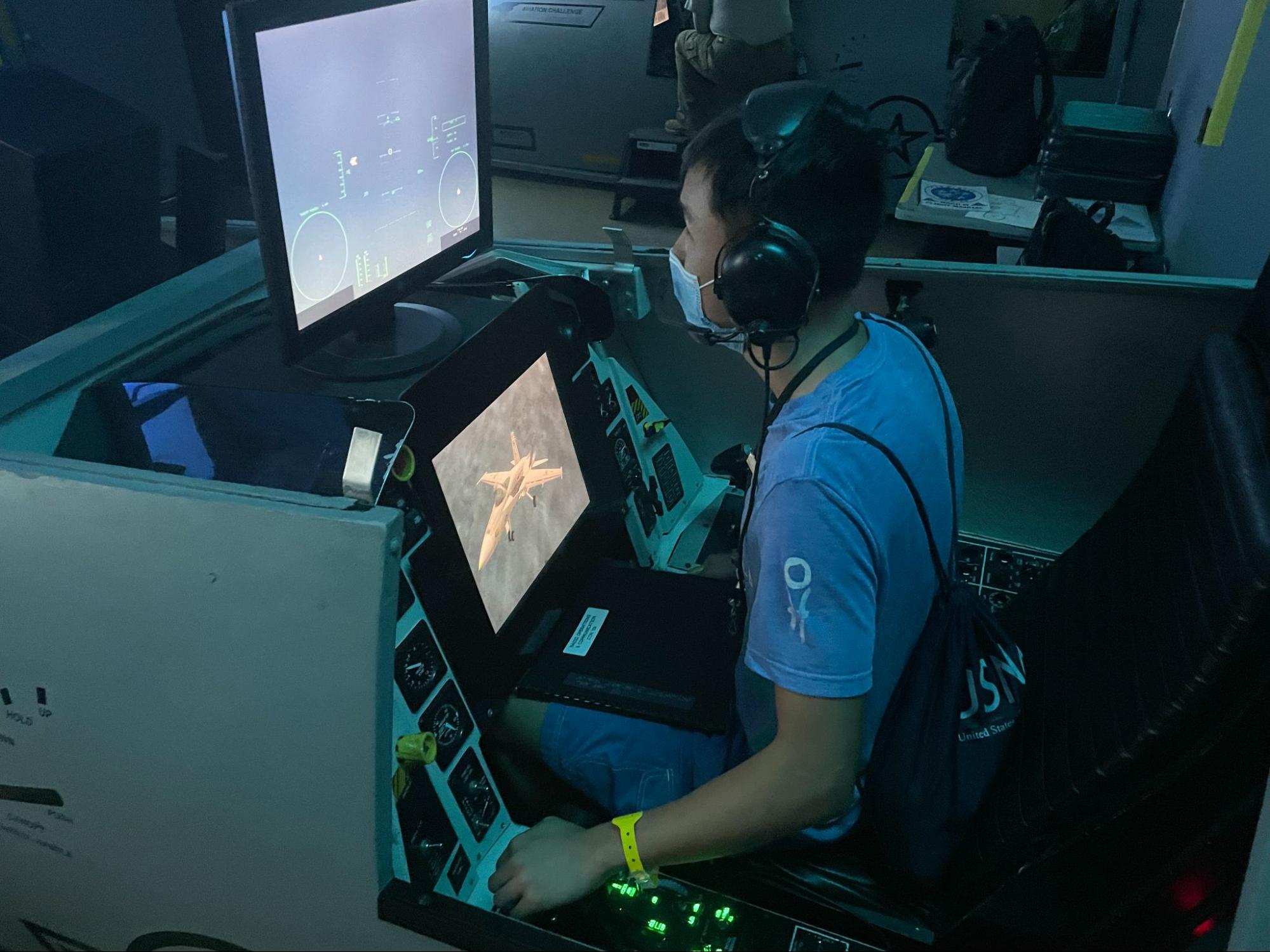 Student wearing headphones sitting in a fighter jet simulator.