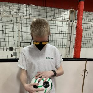 student with short blond hair wearing sunglasses is feeling a soccer ball