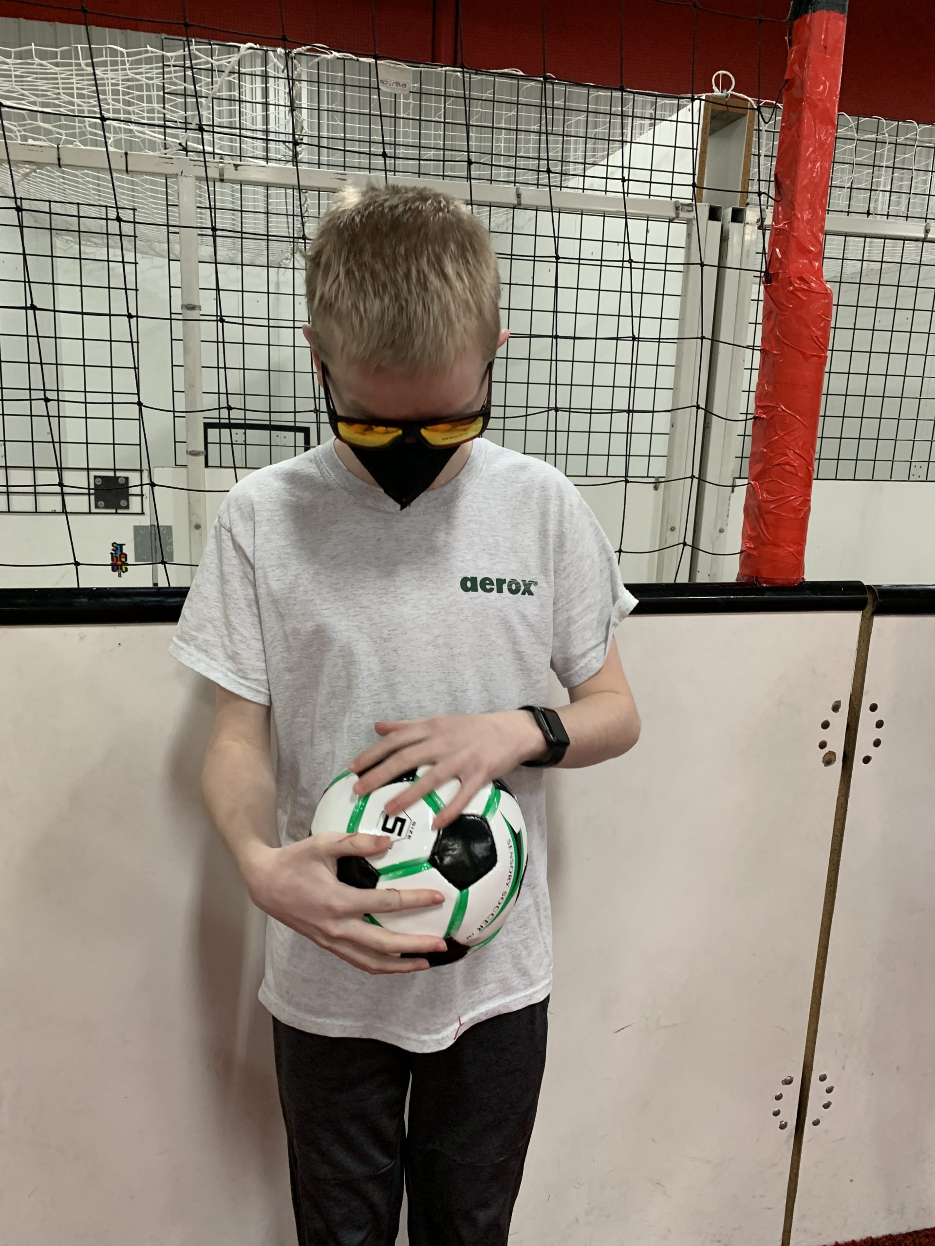 student with short blond hair wearing sunglasses is feeling a soccer ball