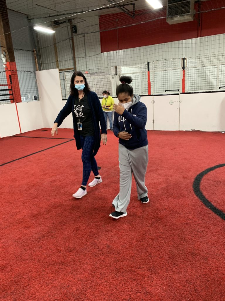 Ms. Kim and a student walk across the width of the soccer field