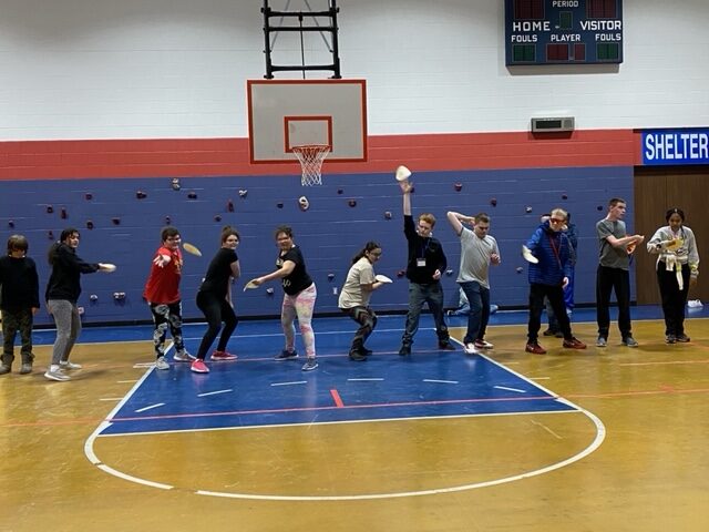 8 students lined up at one end of the KSSB and all are throwing a bean bag