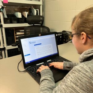 A blonde student works on a laptop