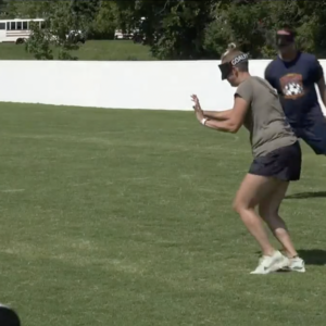 Ms. Nicole wears shorts and t-shirt and is blindfolded ready to kick a soccer ball on a soccer field